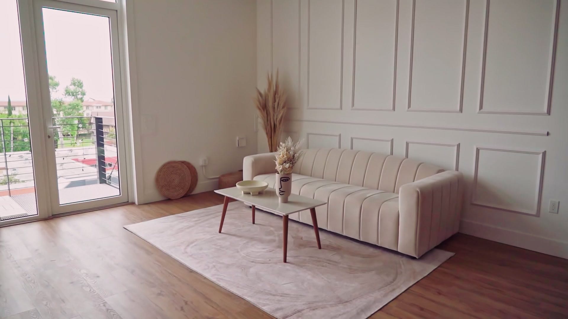 Un salon lumineux avec un canapé crème, une table basse et un bouquet de fleurs séchées